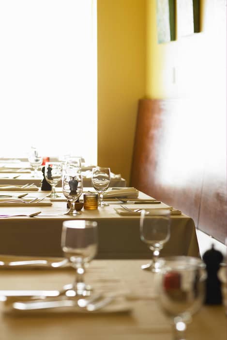 Interior shot of restaurant. Bright image shot across table with wine glasses and place settings.