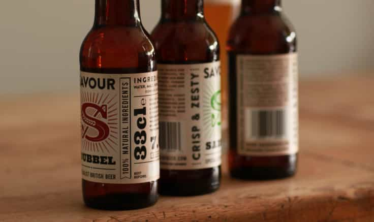 Row of three bottles of Savour beer, each turned to show a different side of the label.